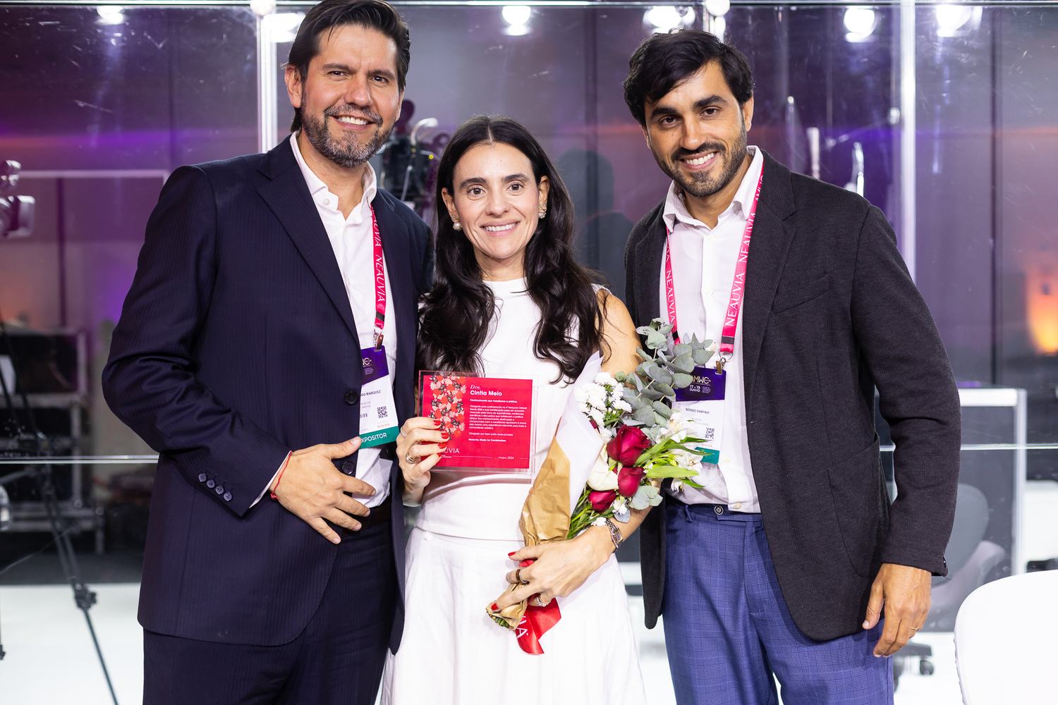 Premiada recebe flores ao lado de dois médicos