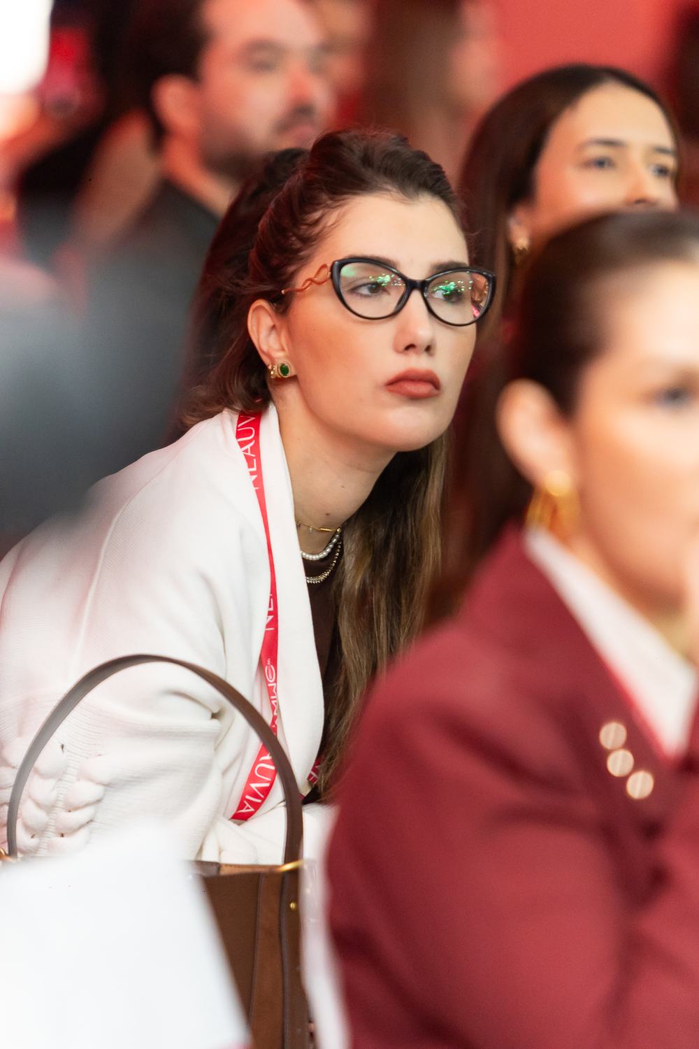 Médica de óculos atenta ao palco